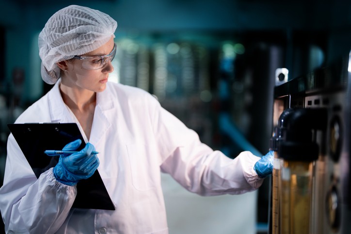 scientist worker checking the quality of Reverse osmosis machine system at the industrial factory. Female worker recording data at the control panel with measure pressure for recycle portable plant.