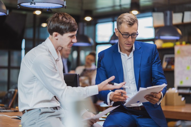 senior financial strategy officier discussing or exchange ideas during working in a tech business office with new financial staff officer with casual relax sitting on table casual meeting discussion