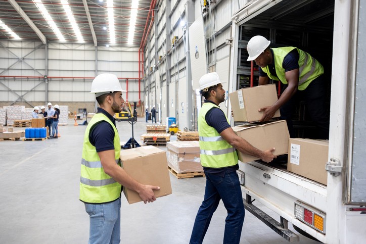 Workers At A Distribution Warehouse Loading Boxes On A Truck