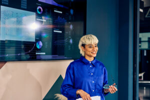 Professional Asian woman presenting data on a digital display in a corporate office. Effective communication and data visualization concept