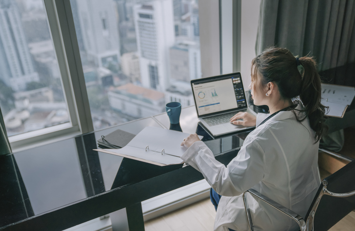 asian chinese female doctor working on medical report with laptop and document file